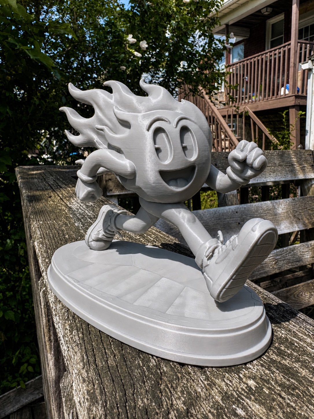 Custom gray 3D-printed running flame character sculpture outdoors