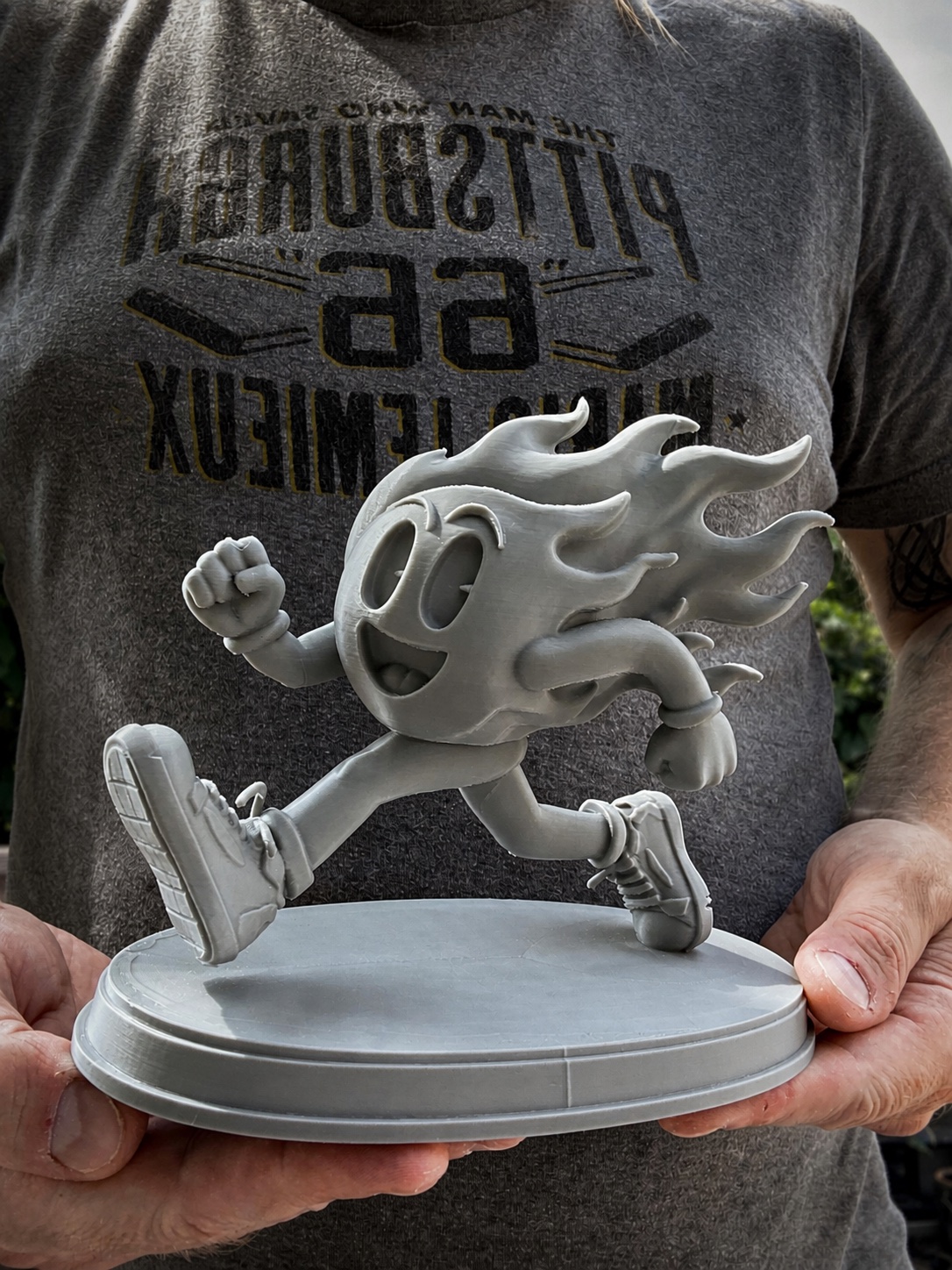 Custom running flame character sculpture held in two hands for scale