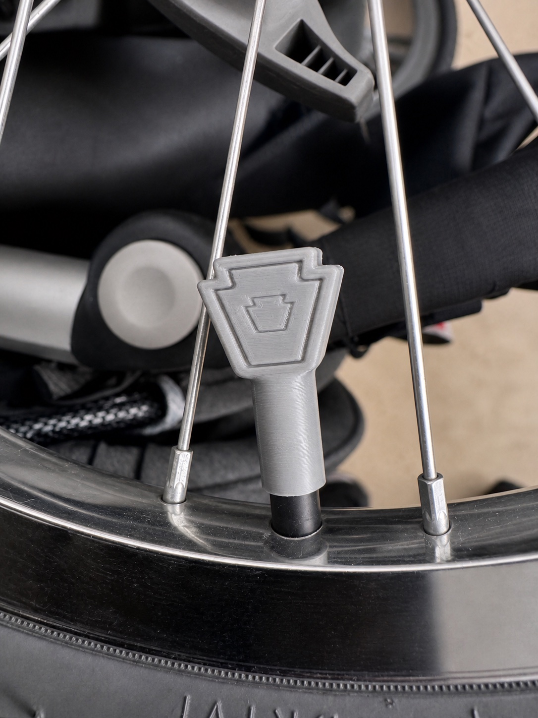 Custom gray Keystone-shaped valve cap installed on a wheel